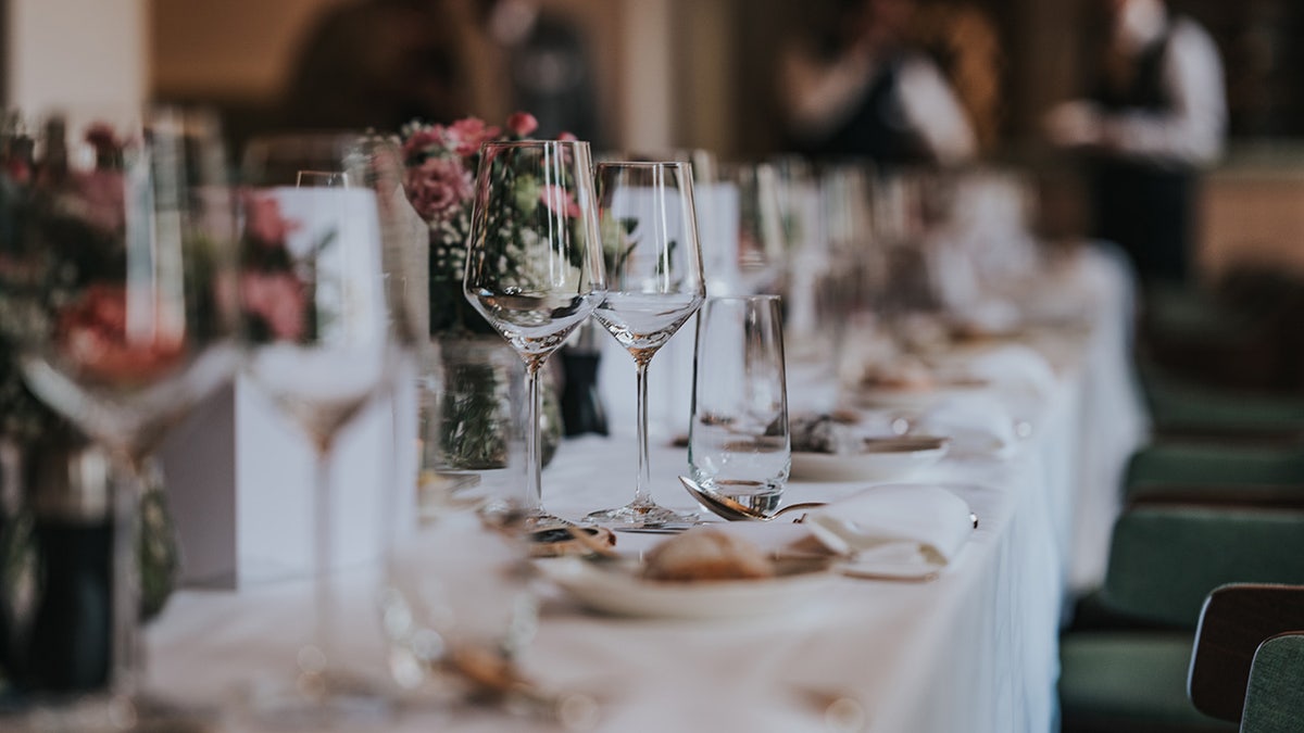 Wedding tablescape arranged with white linen, plates, glasses and pink floral centerpieces.