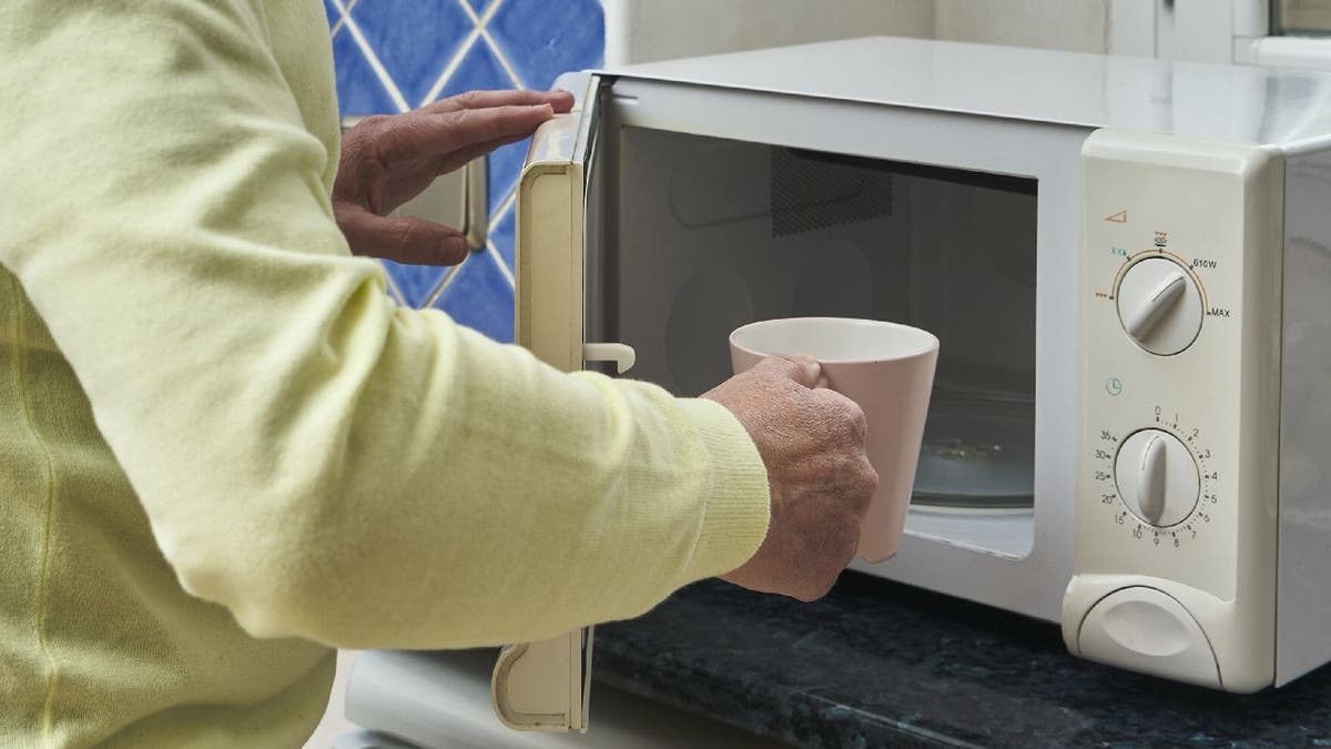 Man puts mug in microwave.