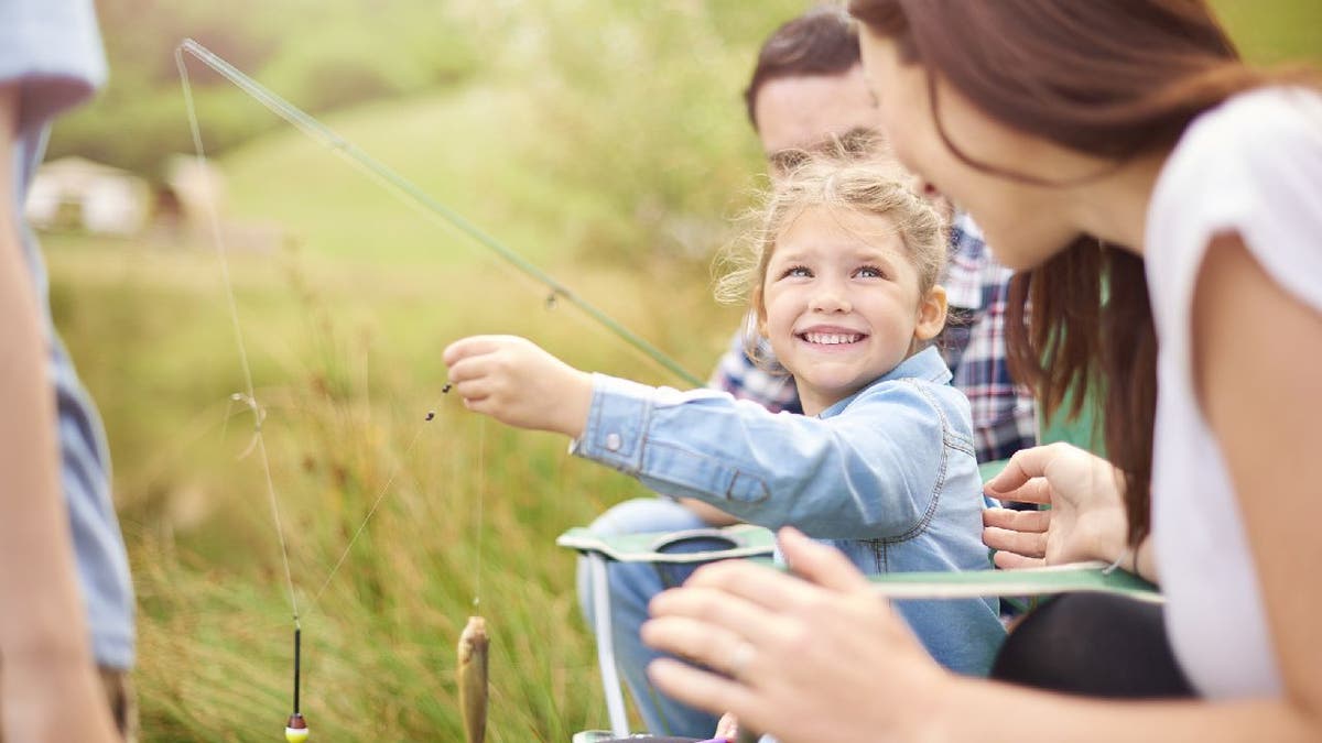 Family goes fishing at a lake.