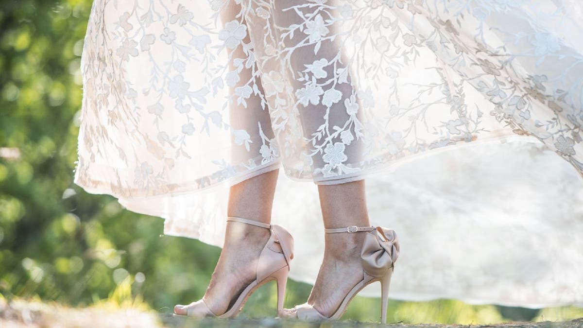 Woman walks in a field with a see-through lace skirt.