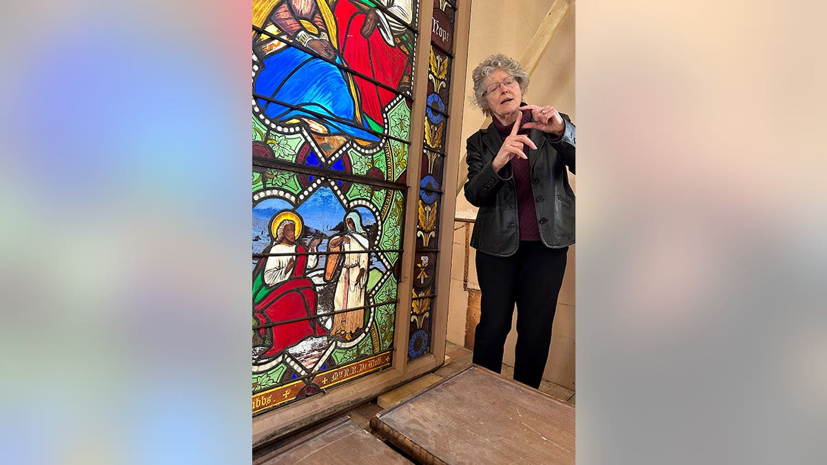 professor standing by stained glass panel