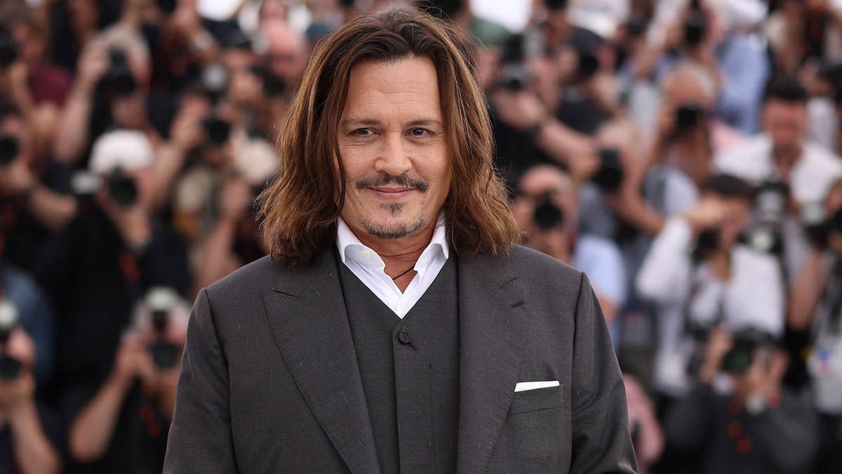 Johnny Depp walks Cannes Film Festival red carpet wearing grey suit with white shirt