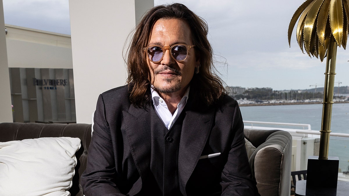 Johnny Depp wears black suit with shirt and glasses 