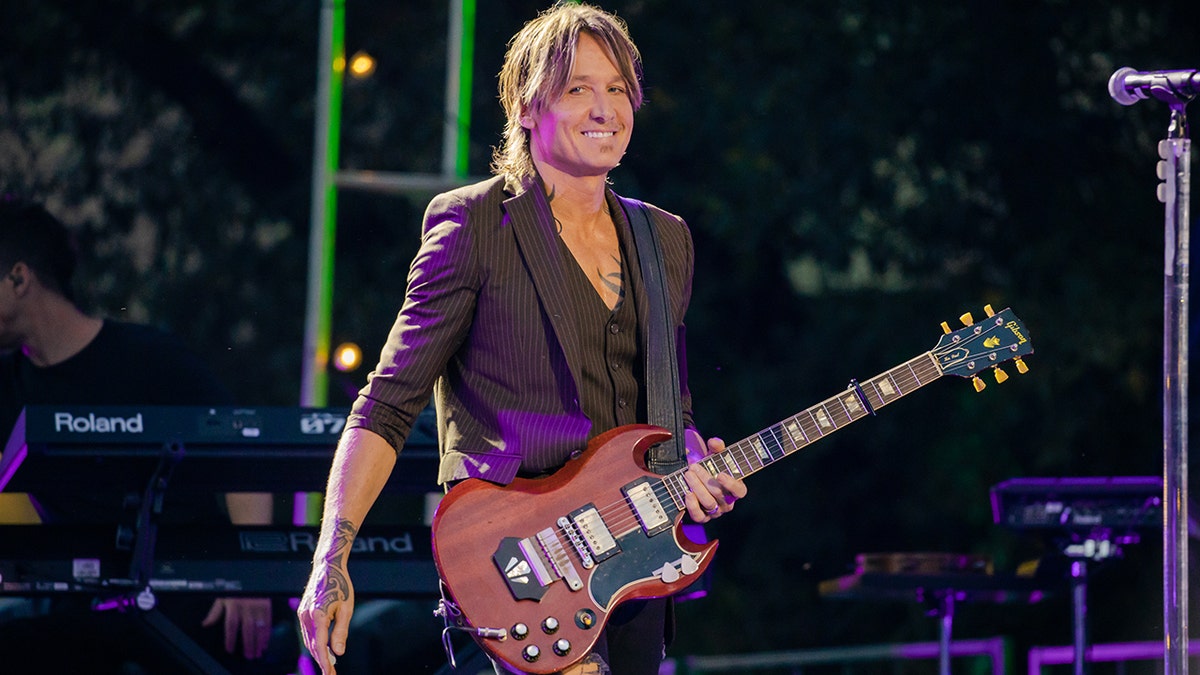 Country star Keith Urban holds guitar during concert