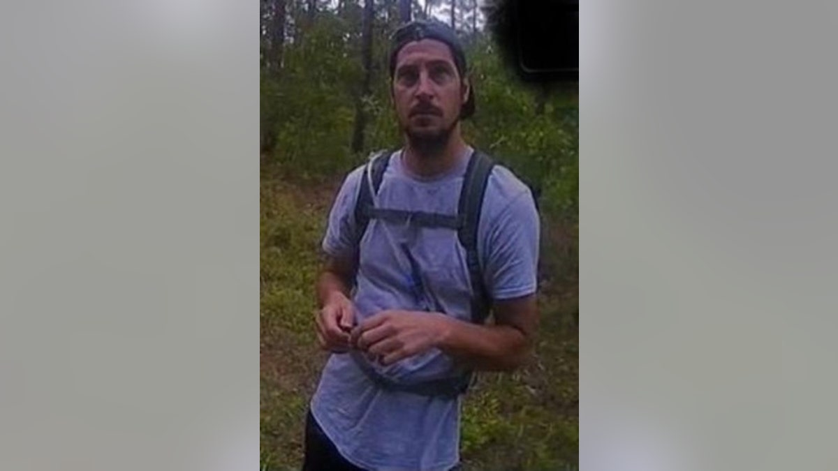 Michael Burham wearing a hat and backpack in the woods