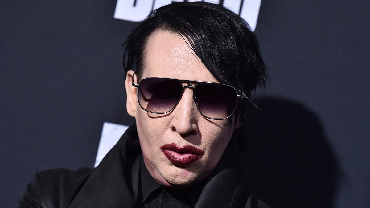 Marilyn Manson wears dark sunglasses and maroon lipstick at red carpet event