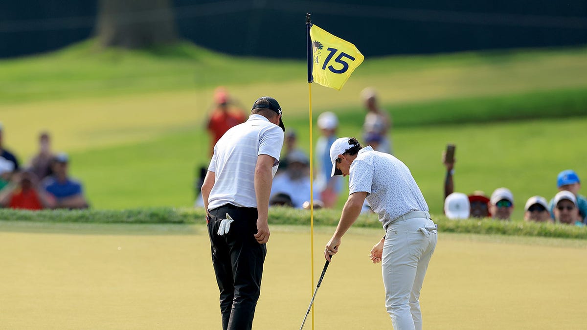 Michael Block and Rory McIlroy look at hole