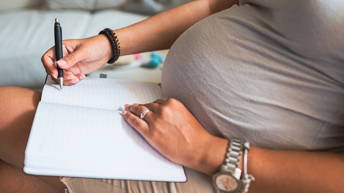 Pregnant woman writing baby names