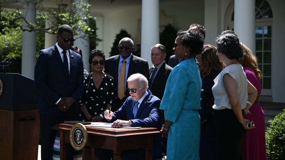 US President Joe Biden (C) signs an executive order on new actions to advance environmental justice