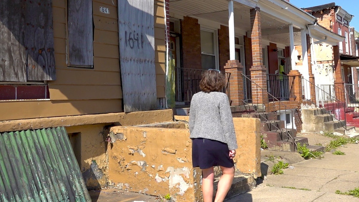 Councilwoman walks in front of boarded up homes in Baltimore, Maryland