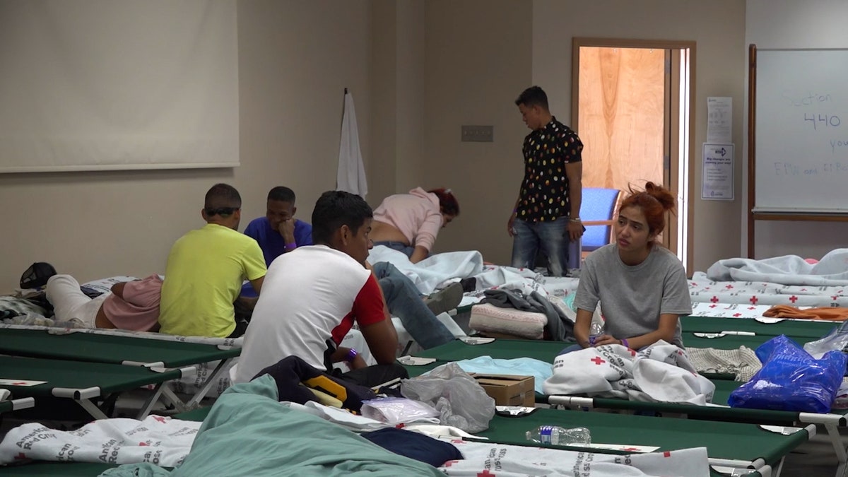 A group of migrants hangout on cots in a shelter