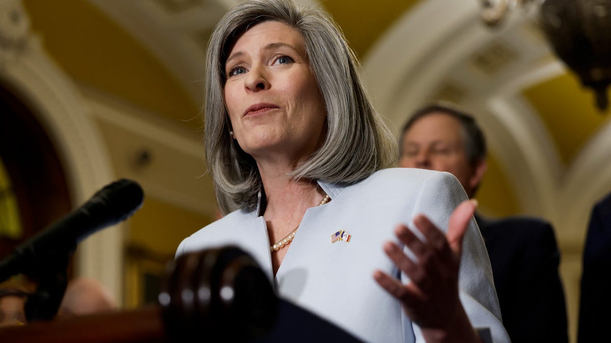 Iowa Senator Joni Ernst speaks at a podium in the halls of Congress