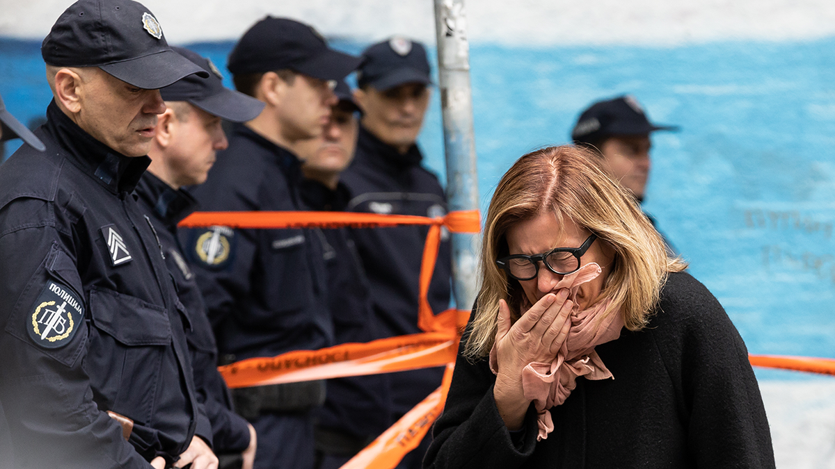 Serbian woman cries into scarf in front of police line