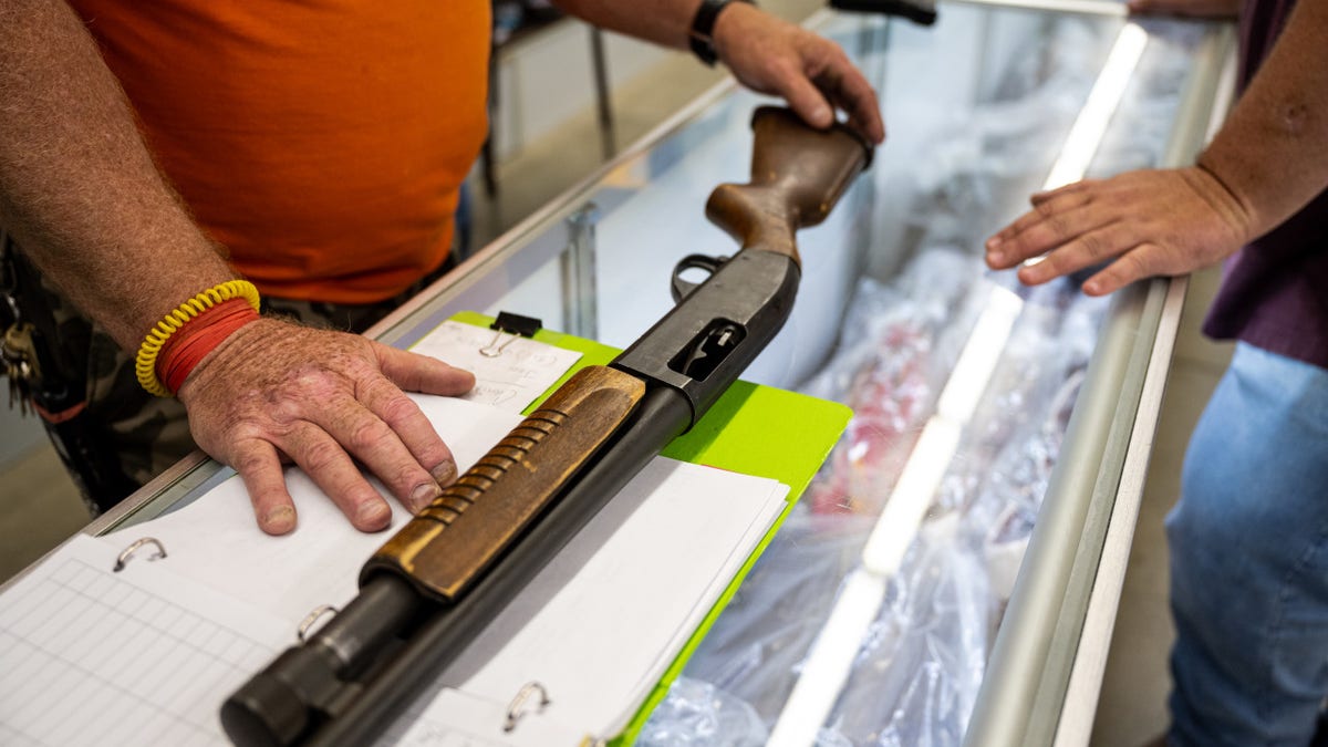 A worker shows a shotgun for sale to a customer at Knob Creek Gun Range in West Point, Kentucky, U.S., on Thursday, July 22, 2021
