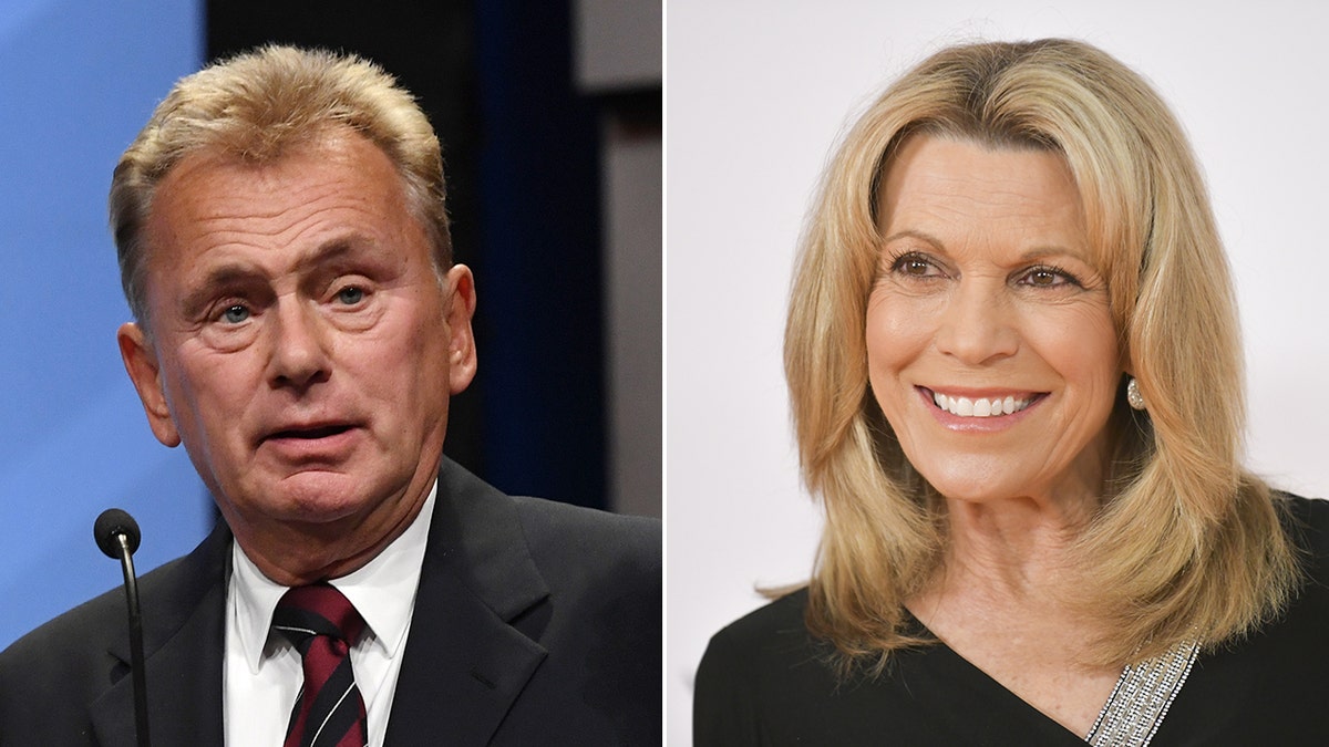 Pat Sajak looks perplexed in a black suit and red and black striped tie speaking behind a podium split Vanna White in black smiles and looks off to her right on the carpet