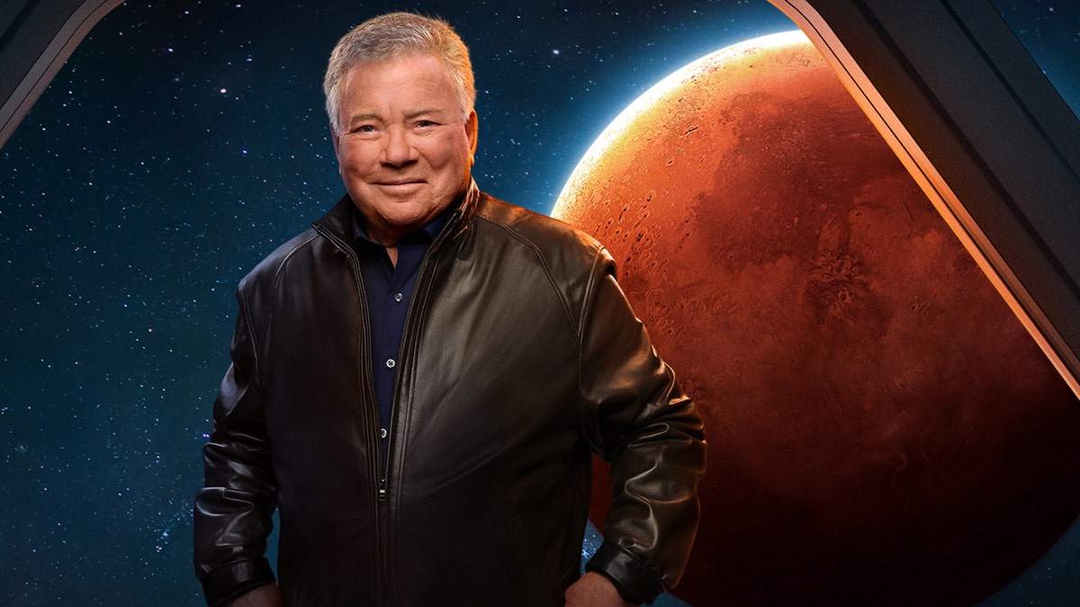 William Shatner wears leather jacket and blue shirt in front of backdrop of Mars