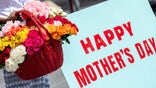 NEW YORK, NEW YORK - MAY 09: A woman holds a large basket of flowers next to a "happy Mother's Day" sign in Washington Square Park on Mother's Day amid the Coronavirus pandemic on May 09, 2021 in New York City. People and families enjoy Mother's Day in anticipation of coronavirus restrictions being lifted on May 19th according to an announcement by New York Governor Andrew Cuomo last week. (Photo by Alexi Rosenfeld/Getty Images)