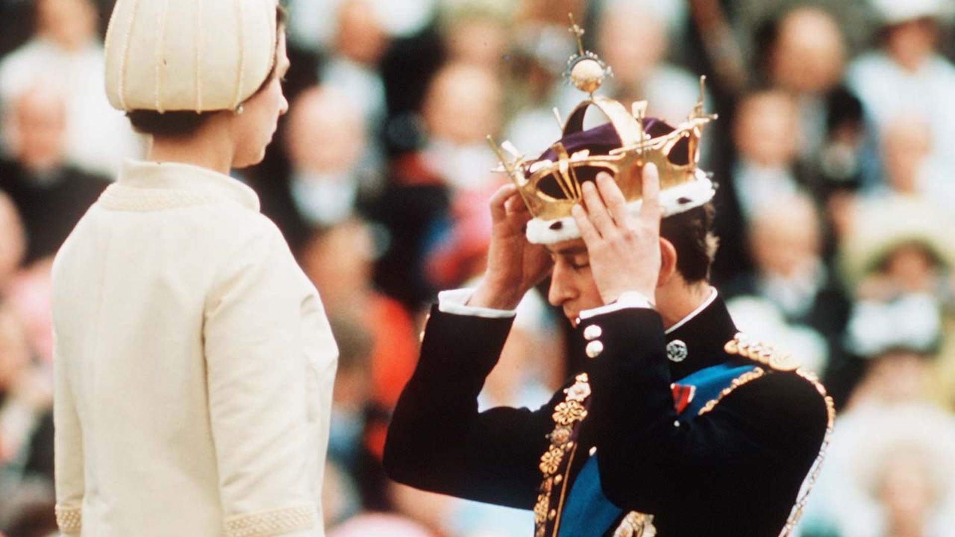 Prince Charles, watched by H.M. Queen Elizabeth II places the gold coronet of The Prince of Wales on his head.