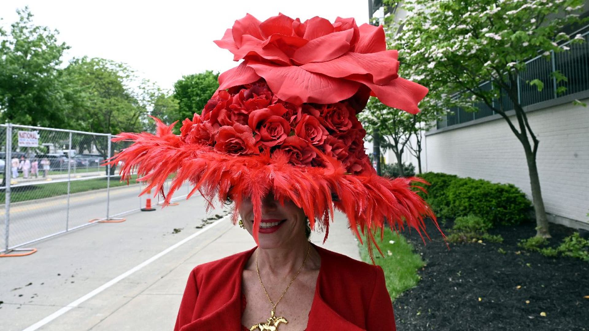 Woman wear a large red hat with roses to the Kentucky Derby.