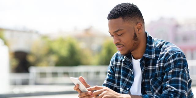 Man in flannel shirt, holding a phone