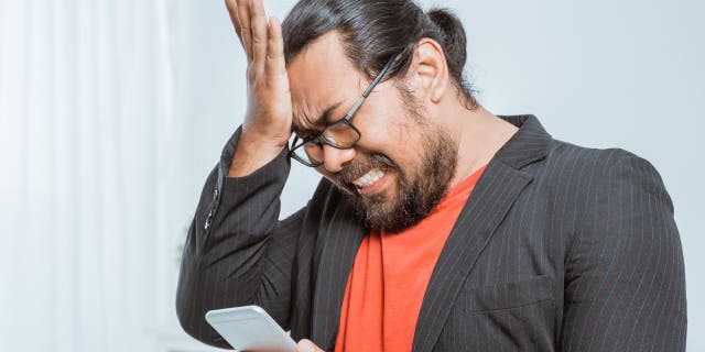Stressed man face palms while on his phone