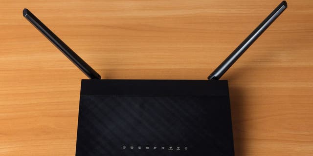 Enrutador wifi negro en un escritorio de madera 
