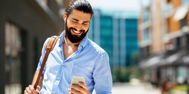 smiling man in blue shirt with smartphone