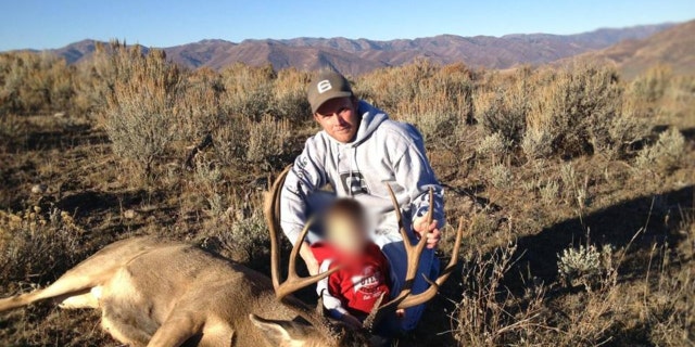 Eric Richins holding a deer with his son