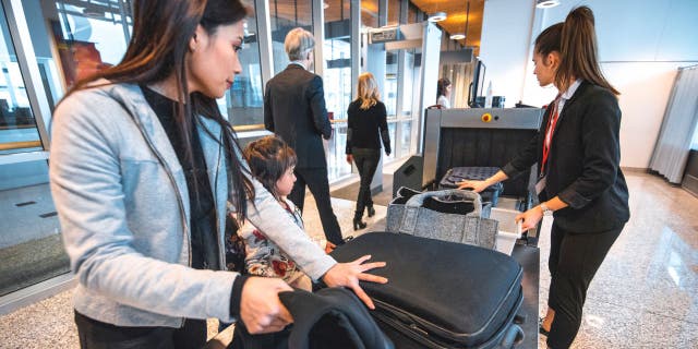 People passing their bags through the machine at the airport.