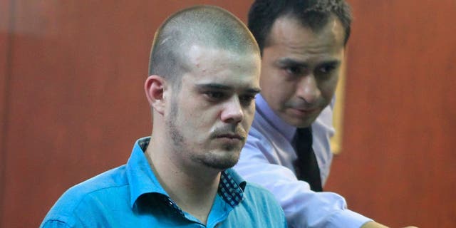 A man directs Dutch citizen Joran Van der Sloot to his seat before the trial in the Lurigancho prison in Lima