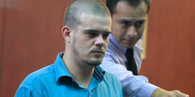 A man directs Dutch citizen Joran Van der Sloot to his seat before the trial in the Lurigancho prison in Lima