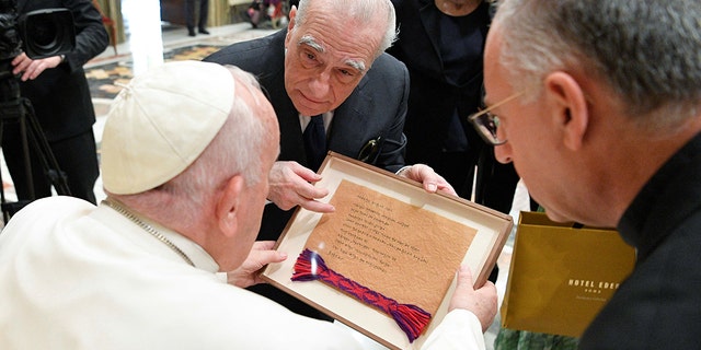 Pope Francis looks down at a frame that Martin Scorsese has presented him with