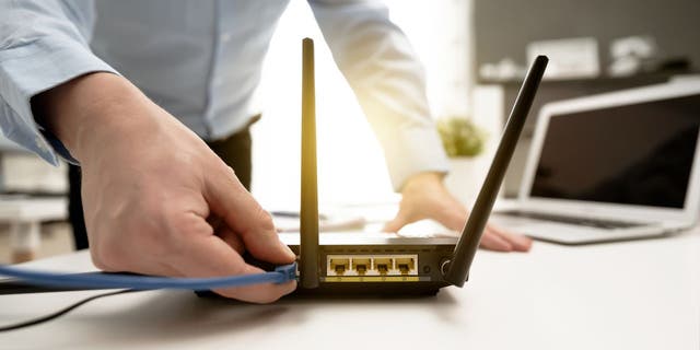 Man plugs wire into wifi router