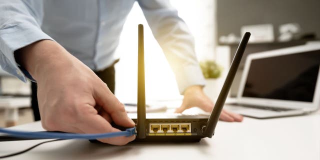 Man plugs wire into wifi router