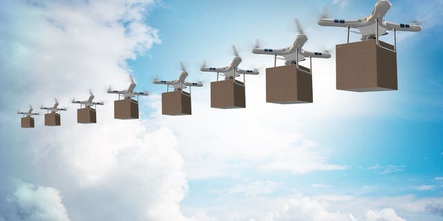 Multiple drones carry boxes in the sky