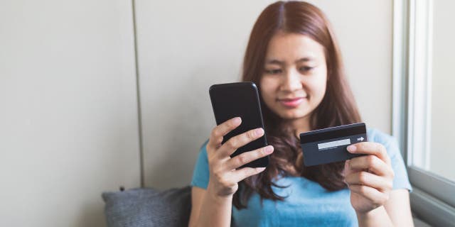 Woman entering her card information into her phone.