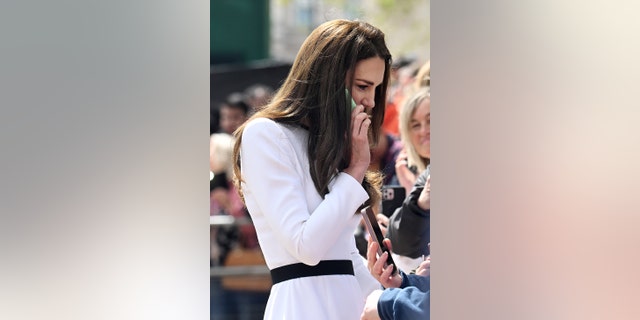 Kate Middleton in a black and white dress talking on a cell phone