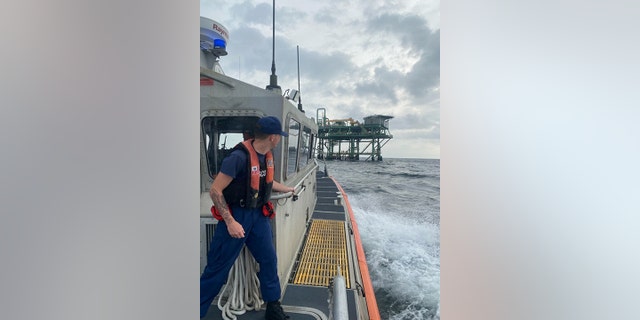 A boat traveling to an oil rig