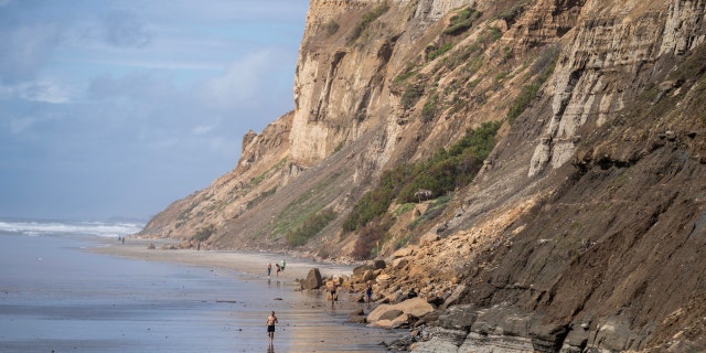 People move past a San Diego, California, bluff collapse