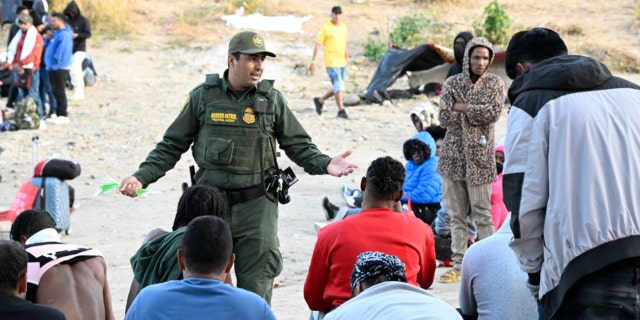 A U.S. Border Patrol agent talks with asylum-seekers