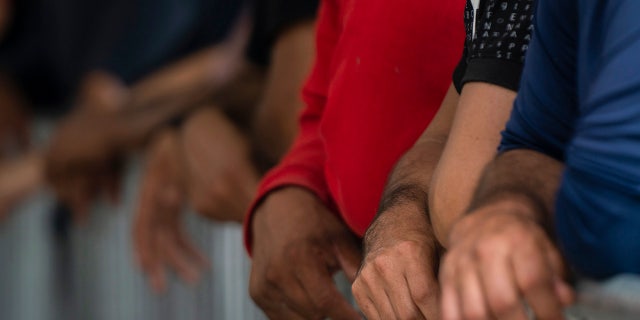 Migrants' hands on gate by port of enntry