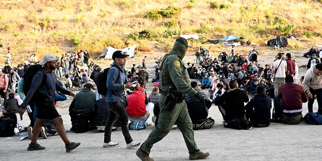 CBP agent walks past crowd of asylum seekers