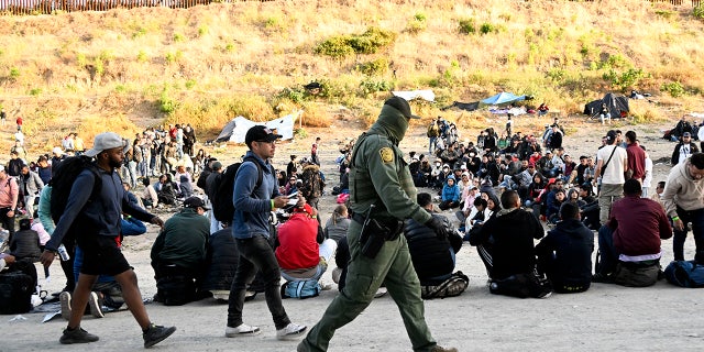 CBP agent walks past crowd of asylum seekers