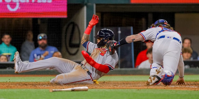 Orlando Arcia slides home as catcher Jonah Heim attempts a tag