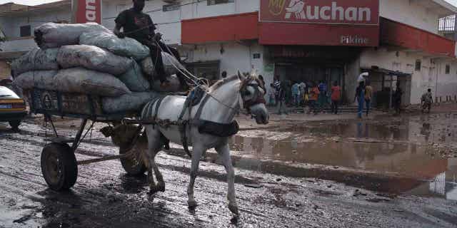 El juicio por violación del principal líder opositor senegalés se aplaza por las protestas 4 Un hombre conduce su carro tirado por caballos frente a un supermercado