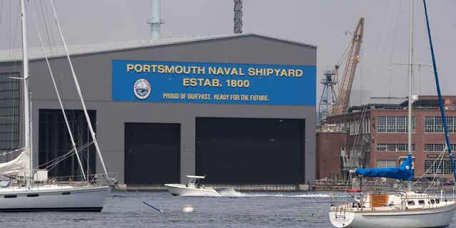 A small pleasure craft passes the Portsmouth Naval Shipyard