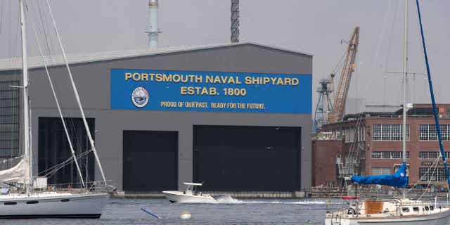 A small pleasure craft passes the Portsmouth Naval Shipyard