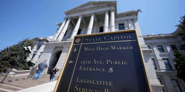 Visitors stand on the west steps of the Colorado Capitol,