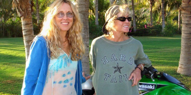 Farrah Fawcett in a grey sweater with Alana Stewart wearing a blue dress