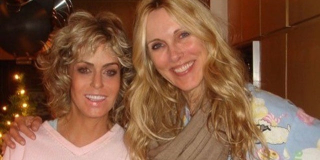 Farrah Fawcett wearing a pink shirt next to Alana Stewart wearing a blue sweater